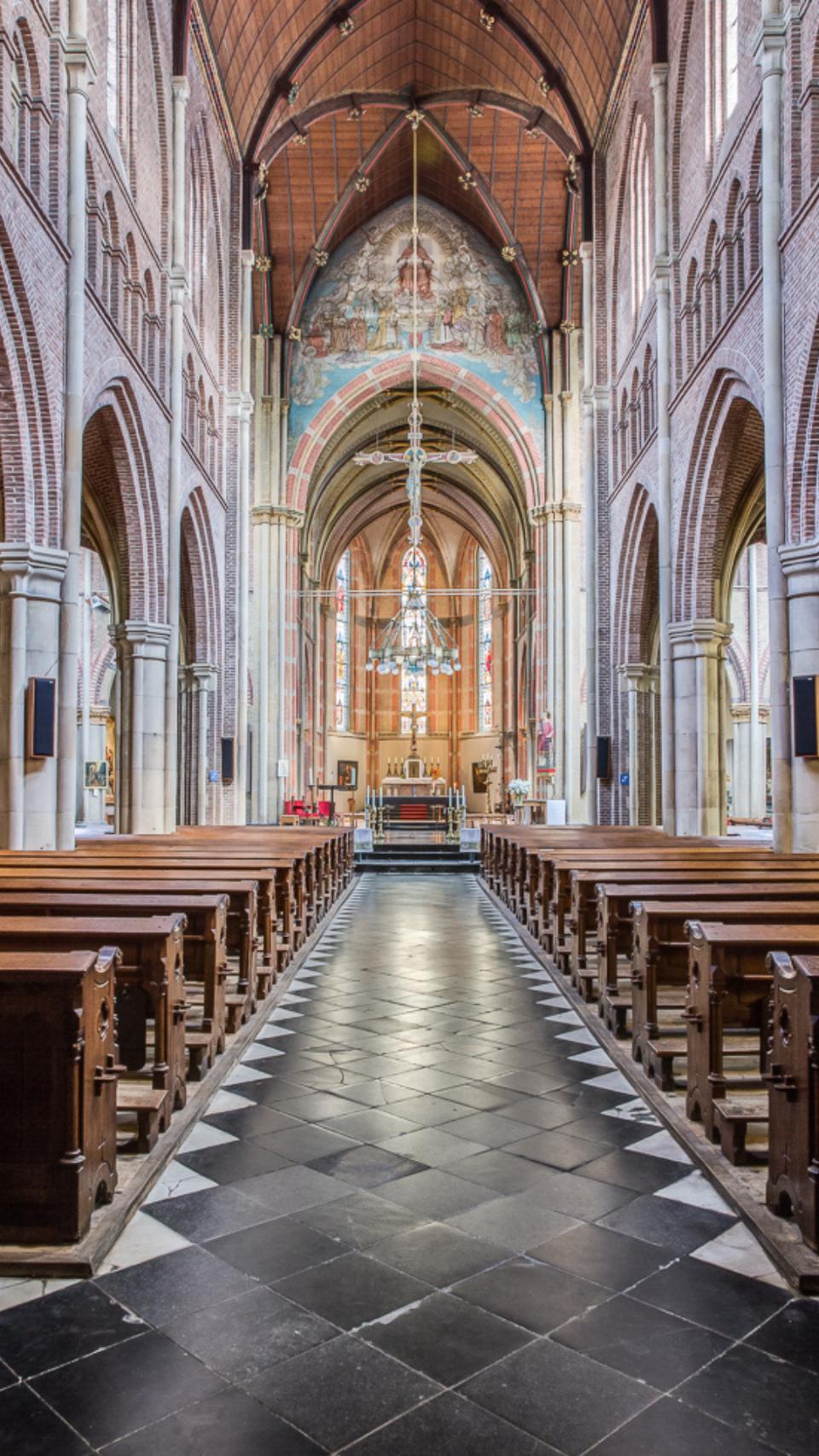 Binnenkant St. Laurentiuskerk met houtenbanken links en rechts